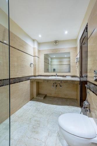 a bathroom with a toilet and a sink and a mirror at Alaya Stays Hotel Emperor Palms in New Delhi