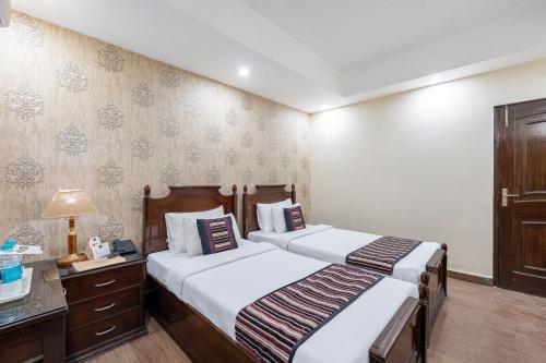 a bedroom with two beds and a desk with a lamp at Alaya Stays Hotel Emperor Palms in New Delhi