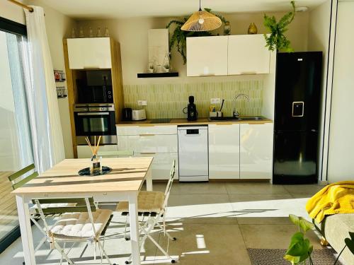 Il comprend une cuisine équipée d'une table et d'un réfrigérateur noir. dans l'établissement Maison ensoleillée climatisée avec terrasse et parking, à Saint-Victor-la-Coste