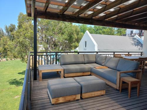 a patio with a couch and tables on a deck at De Zalze Lodge in Stellenbosch
