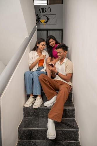 three people sitting on stairs looking at a cell phone at Vib O Stay in Pune