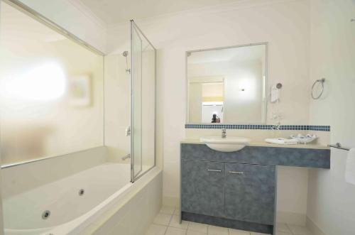 a bathroom with a tub and a sink and a shower at Ivory Palms Resort Noosa in Noosaville