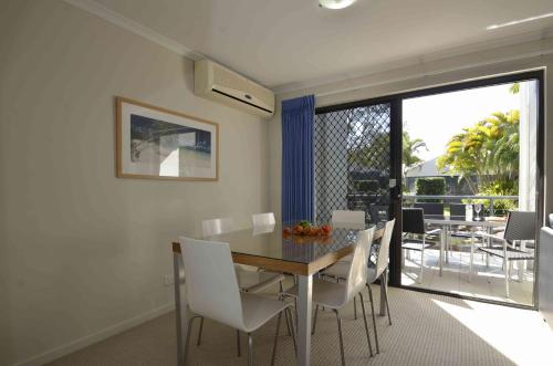 a dining room with a table and white chairs at Ivory Palms Resort Noosa in Noosaville