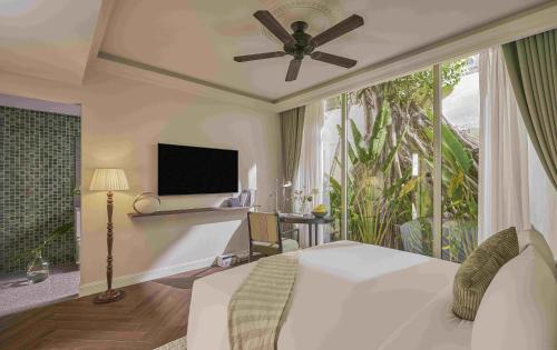 a bedroom with a bed with a ceiling fan and a window at President Maison Signature By M Village in Ho Chi Minh City