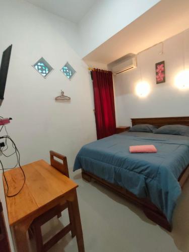 a bedroom with a bed and a wooden table at Jatisela homestay in Midang