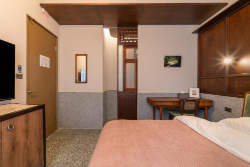 a bedroom with a bed and a desk and a television at 安樓文旅 Enzo House in Keelung