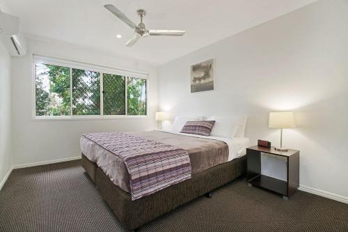 a white bedroom with a bed and a window at Ivory Palms Resort Noosa in Noosaville