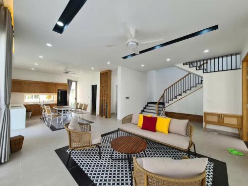 a living room with a couch and chairs and a staircase at Swanbay - KaKa's House in Cù Lao Ong Con