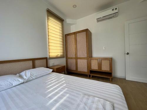 a bedroom with a large white bed and a window at Swanbay - KaKa's House in Cù Lao Ong Con