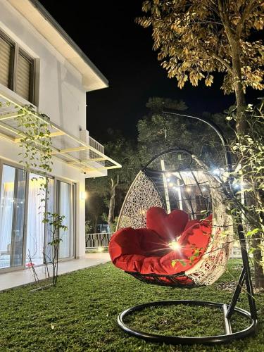 a red umbrella sitting on the grass near a house at Swanbay - KaKa's House in Cù Lao Ong Con