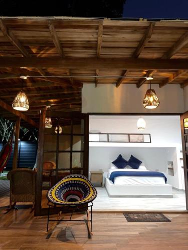 a bedroom with a bed and a chair on a deck at Río Celeste Poshtel Tayrona - Zaino in Calabazo