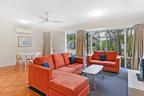 a living room with orange furniture and a table at Ivory Palms Resort Noosa in Noosaville