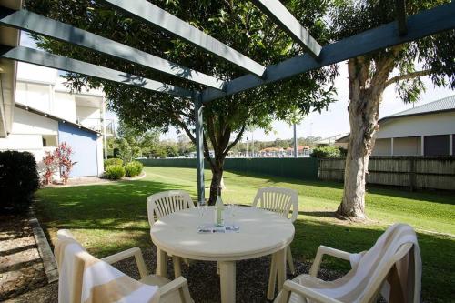 a white table and chairs under a pergola at Ivory Palms Resort Noosa in Noosaville