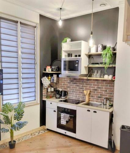 une cuisine avec des placards blancs et un mur en briques dans l'établissement Halte - Illinois, aux Andelys