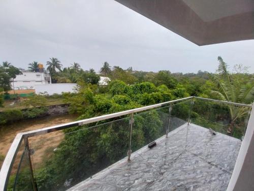 a glass balcony with a view of a forest at Mirnalini Homestays in Mahabalipuram