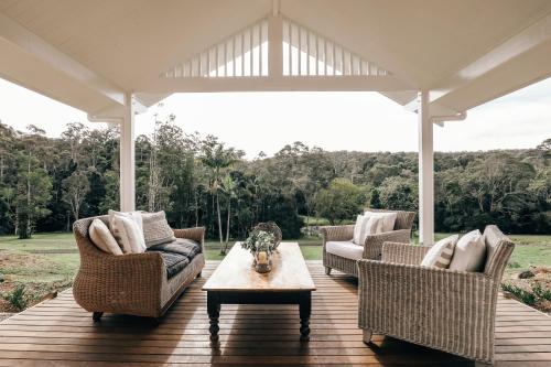 a porch with couches and a coffee table on a wooden deck at Nightcap Ridge - Byron Bay Hinterland in Dorroughby