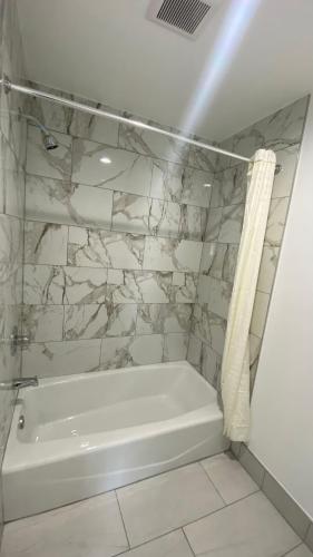 a white bath tub in a bathroom with a stone wall at Plaza Inn Motel - Los Angeles area in Rosemead