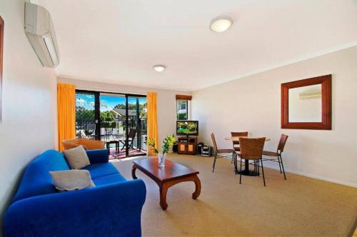 a living room with a blue couch and a table at Ivory Palms Resort Noosa in Noosaville