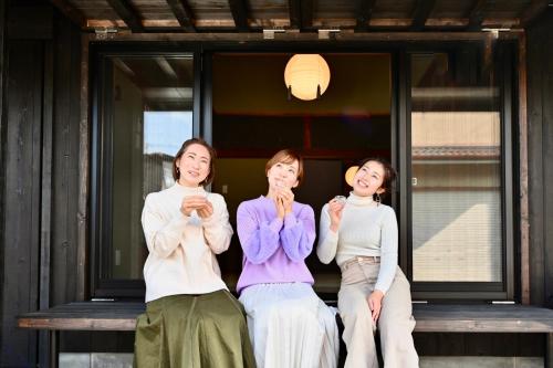 a group of three women sitting on a bench at 御宿Fuku in Kannoura