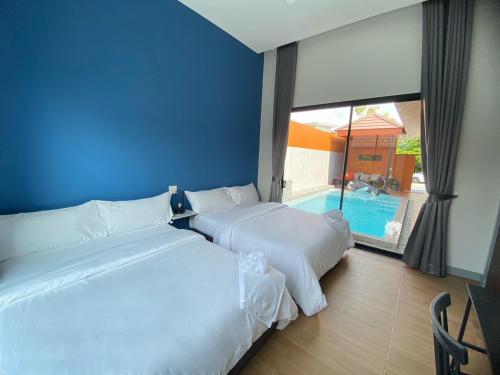 two beds in a hotel room with a swimming pool at Bluda Poolvilla B in Hat Yai
