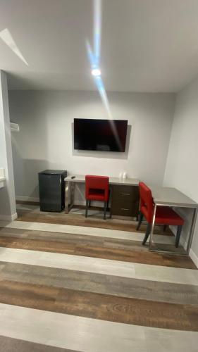a room with two red chairs and a table and a tv at Plaza Inn Motel - Los Angeles area in Rosemead