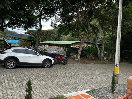 a white car parked next to a motor scooter at Casa Jacinto in Ciudad Bolívar