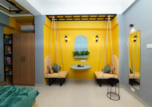 a yellow room with two chairs and a table at Vib O Stay in Pune