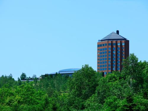 a tall building in the middle of trees at Furano Resort Orika in Nakafurano