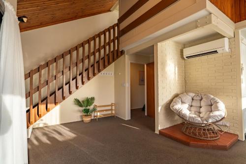 a living room with a chair and a staircase at River City Views With Spa Pool, BBQ & Sky TV in Whanganui