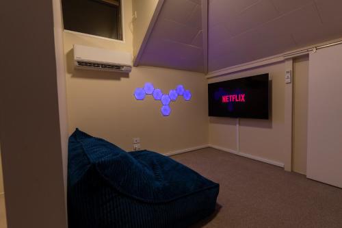 a room with a blue couch and a tv at River City Views With Spa Pool, BBQ & Sky TV in Whanganui
