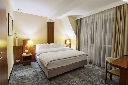 a hotel room with a large bed and a desk at Hotel Na Półboru in Sieradz