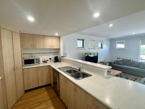 a kitchen with a sink and a living room at Seventy at Cape View Resort in Busselton