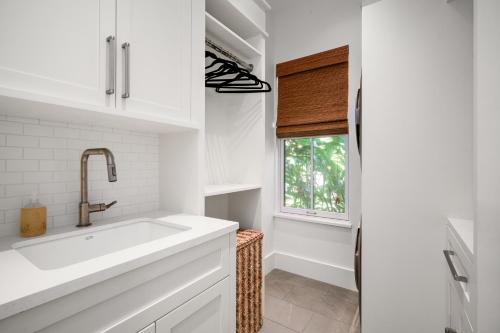 Una cocina blanca con fregadero y ventana. en Kukuiula Vacation Home #57, en Koloa