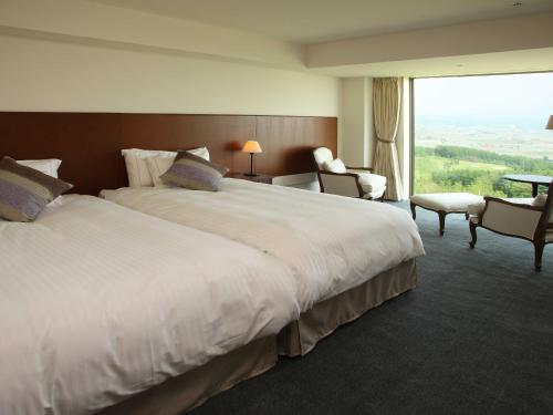 a hotel room with two beds and a large window at Furano Resort Orika in Nakafurano