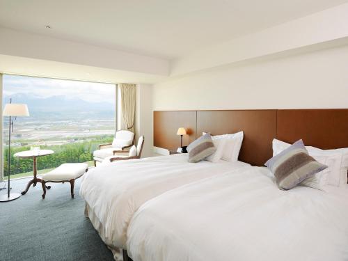 a hotel room with a large bed and a large window at Furano Resort Orika in Nakafurano
