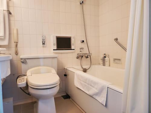 a bathroom with a toilet and a tub and a television at Furano Resort Orika in Nakafurano
