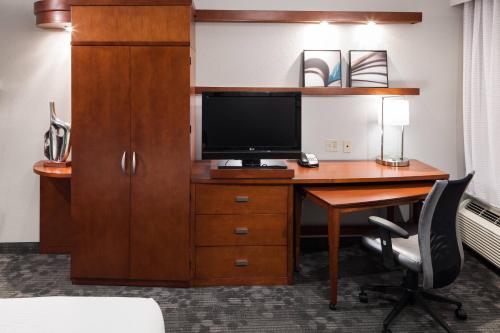 a hotel room with a desk with a television and a cabinet at Courtyard by Marriott Miami at Dolphin Mall in Miami