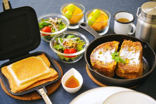 a table with a pan with bread and toast and salad at COUSCOUS Glamping Manazuru in Manazuru
