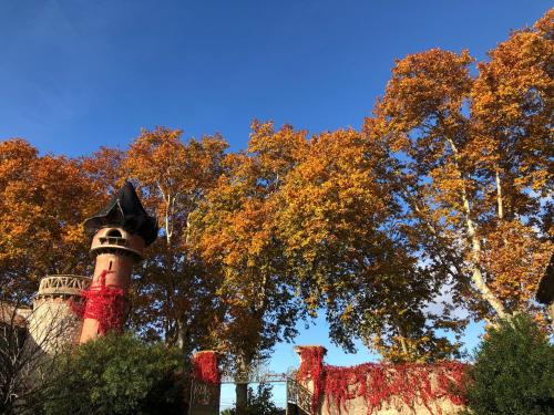a tower in front of trees with autumn leaves at Terrasse avec vue Domaine Viticole in Sallèles-dʼAude