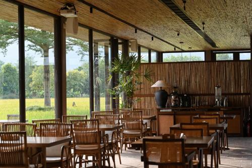 a dining room with tables and chairs and windows at Sanhe Daoli Resort in Qingyuan