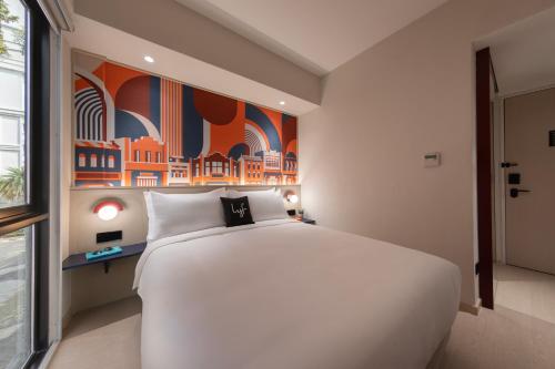 a large white bed in a room with a painting at lyf Georgetown Penang in George Town