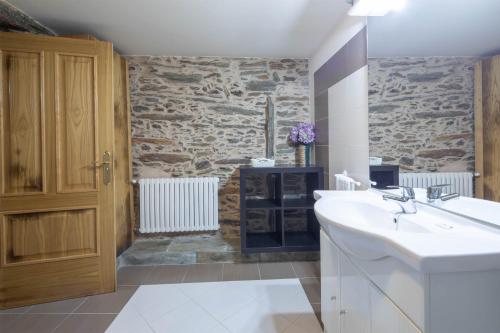 a bathroom with a sink and a stone wall at Oforno do curro-habitación adaptada in Boborás