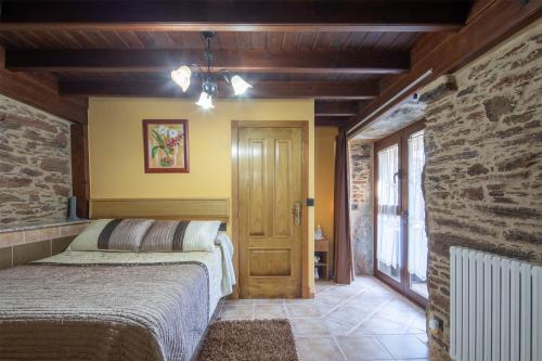 ein Schlafzimmer mit einem Bett in einem Zimmer mit einer Steinmauer in der Unterkunft O Forno do Curro -Casa da Amendoa in Boborás