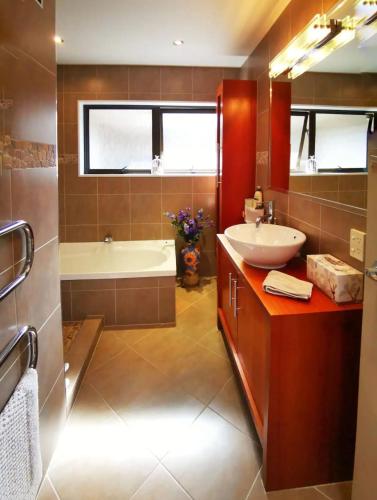 a bathroom with a tub and a sink and a bath tubermottermott at Acacia Bay Lodge- Private Manor with Lake and Garden views in Taupo