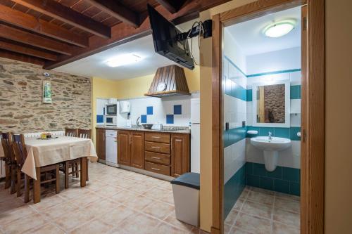 a kitchen with a dining table and a sink at O forno do curro- Casiña da Noz in Boborás