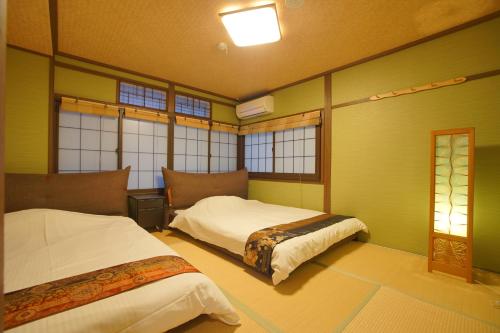 two beds in a room with green walls and windows at 伏見稲荷の宿-Inari no Yado- in Kyoto