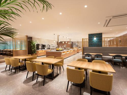 a restaurant with wooden tables and chairs and a kitchen at Namba Oriental Hotel in Osaka