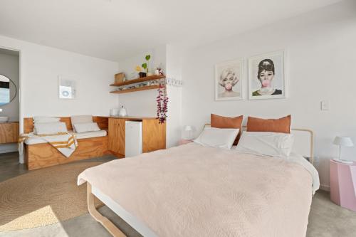 a white bedroom with a large bed and a table at Black Barn Escape in Nelson