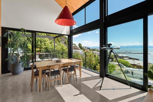 a dining room with a table and a view of the ocean at Black Barn Escape in Nelson
