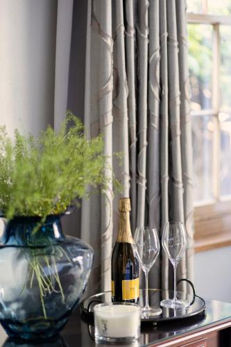 a bottle of wine sitting on a table with two wine glasses at Lemoenkloof Boutique Hotel in Paarl